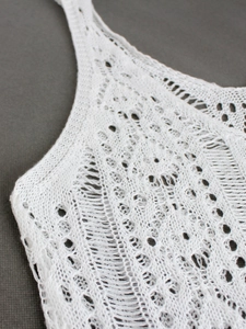 Close-up of white crochet knit fabric with hollow mesh patterns for beachwear dress