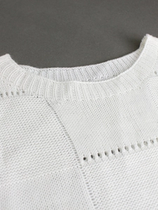 Detail of white knit top showing ribbed neckline and intricate openwork textures