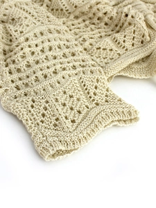 Close-up of beige pointelle knit fabric showing breathable hollow textures on sleeve