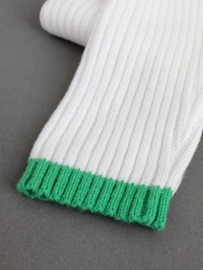 Détail d'un pull en maille épaisse blanche avec poignets côtelés vert vif