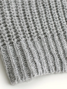 Close-up of gray ribbed knit texture on long sleeve sweater cardigan cuffs