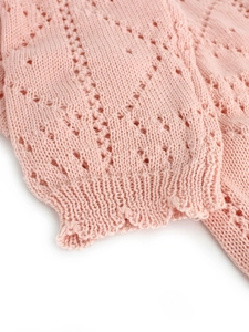 Close-up of light pink knit cardigan with delicate pointelle diamond stitch pattern