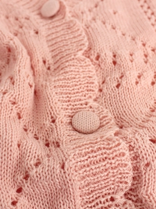 Close-up of pink V-neck cardigan featuring delicate hollow-out knitting and fabric buttons