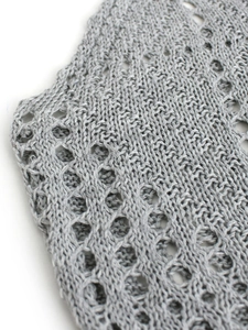 Détail macro du motif en maille crochetée grise ajourée sur la robe sans manches