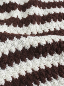 Macro shot of brown and white zigzag knit pattern on a soft V-neck sweater vest