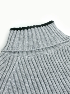 Détail d'un pull à col roulé gris chiné avec bordure noire et texture en maille côtelée