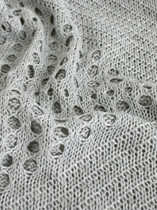 Détail macro du tissu tricoté gris clair avec motifs crochetés géométriques ajourés