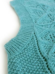 Detail of mint green knitted sweater vest featuring ribbed round neck and hollow pattern