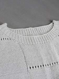 Detail shot of the crew neckline and intricate knit texture on a grey casual sweater