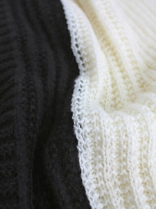 Close-up of thick cable knit texture in black and cream white honeycomb pattern