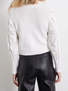 Detail of white knit cardigan featuring hollow diamond patterns and premium textured finish