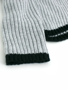 Détail du poignet en maille côtelée gris clair avec bordure noire contrastée