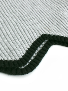 Détail des poignets en tricot côtelé sur un pull à col roulé gris avec bordure noire