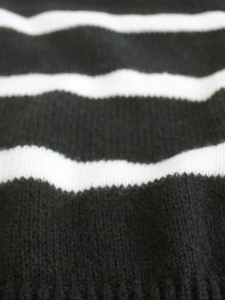 Close-up of black and white striped knit fabric with detailed ribbed hem texture
