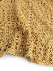Vue macro détaillée du tissu tricoté jaune moutarde avec motifs losanges ajourés