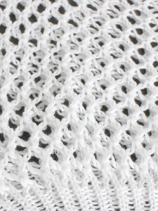 Macro detail of the white openwork crochet mesh fabric on this long sleeve knitted sweater