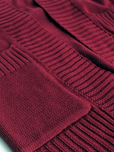 Macro shot of burgundy knit texture and ribbed stitching details on the cardigan