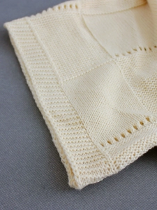 Detailed macro shot of cream knit texture with intricate crochet patchwork pattern