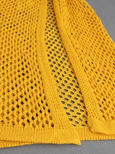 Detailed macro view of yellow crochet knit mesh fabric with honeycomb pattern
