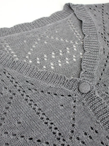 Detail of dark grey knit cardigan with hollow-out diamond pattern and ribbed neckline