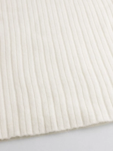 Dettaglio ravvicinato della trama in maglia a coste bianco crema e finiture di pregio