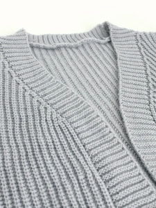 Detailed macro view of light grey knit cardigan showing thick vertical ribbed texture