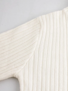 Dettaglio del maglione a coste bianco che mostra cuciture e trama della spalla