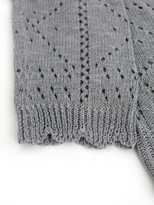 Close-up of gray knit cardigan sleeve with diamond pointelle pattern and ribbed cuffs