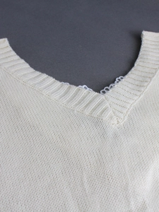 Detail of V-neckline featuring refined ribbed knit texture and delicate white lace trim