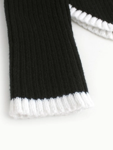 Vue macro des poignets en tricot côtelé contrasté noir et blanc sur un pull à manches