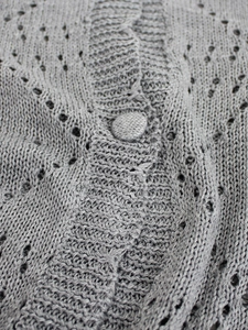 Detail of gray pointelle knit cardigan featuring elegant wave texture and fabric-covered button