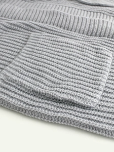 Detailed view of light grey knit sweater showing chunky ribbed texture and square pocket