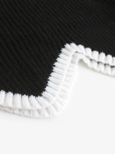 Vue détaillée du bord festonné blanc contrasté sur le tissu en tricot noir