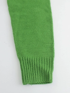 Detail of green knitted sweater sleeve with elastic ribbed cuffs and textured stitch pattern