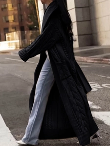 Detail of black cable-knit long cardigan featuring thick texture and ankle-length cut