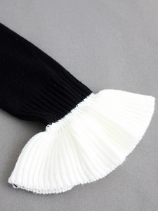 Détail de manche en tricot noir avec poignets évasés à volants blancs plissés