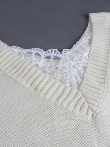 Detailed macro view of cream V-neck knit sweater featuring elegant white lace trim accents
