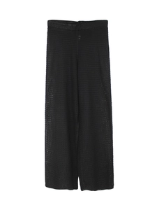 Close-up of black crochet knit trousers showing detailed mesh texture and hollow pattern