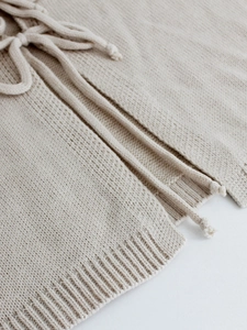 Gros plan du tissu en maille beige avec cordons et ourlet côtelé sur la veste à manches longues