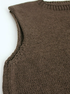 Detailed close-up of brown knit vest showing ribbed crewneck and textured fabric pattern