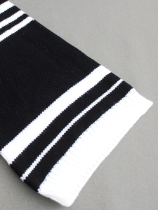 Close-up of a black knit sweater dress featuring white striped ribbed cuffs and hem