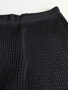 Close-up of black crochet knit pants showing intricate mesh texture and waistband details