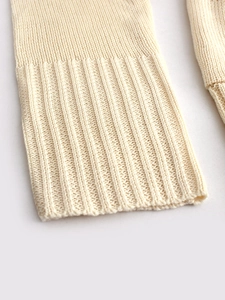 Close-up of ribbed cuffs on a cream-colored long-sleeve knit cardigan sweater