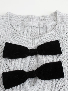 Light gray cable knit sweater dress with black velvet bows and textured stitching