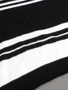 Detailed macro view of black and white striped knit fabric texture with ribbed hem finish