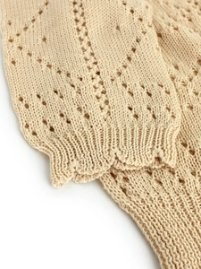 Detail of beige V-neck cardigan featuring pointelle diamond knit and ribbed cuffs