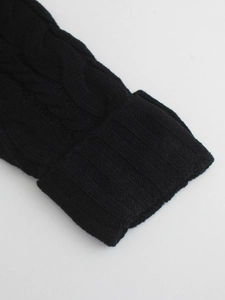 Detail shot of the chunky cable knit pattern and ribbed cuff on a black cardigan sleeve