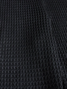 Close-up of black honeycomb knit fabric showing intricate breathable mesh texture