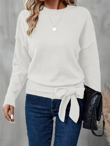 Detail of white knit sweater showing large side-tie bow and ribbed hemline texture
