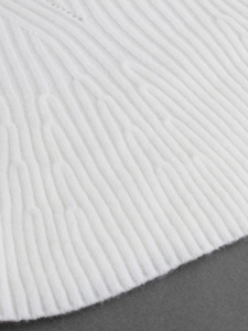 Close-up of white knitted sweater with premium textured patterns and ribbed hem detail